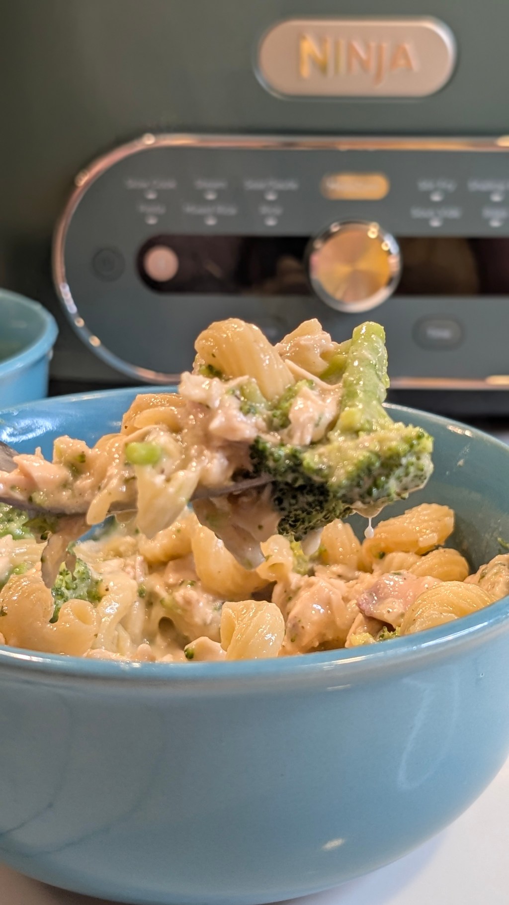A blue bowl of creamy Boursin chicken and broccoli cavatappi pasta