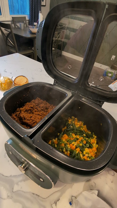 Sloppy Joe filling cooking in one zone of a Ninja multicooker with vegetables in the other